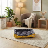 Panier pour animal jaune vif avec rebords moelleux gris, disposé dans un intérieur de salon lumineux avec une décoration moderne et des plantes vertes.