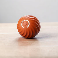 Happy Animalia orange interactive dog ball with swirling texture and illuminated power button for mental stimulation.
