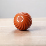 Happy Animalia orange interactive dog ball with swirling texture and illuminated power button for mental stimulation.